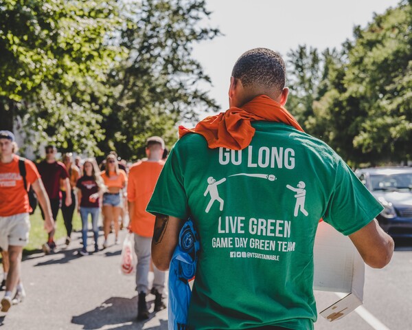 A man holds a recycling bag wearing a green t-shirt that says “Go Long, Live Green.”