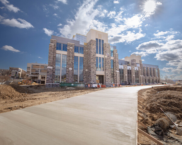 Grey Hokie Stone Hitt Hall with unfinished landscaping on a sunny day.
