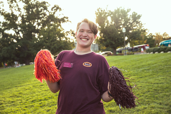 A student holding maroon and orange pompoms