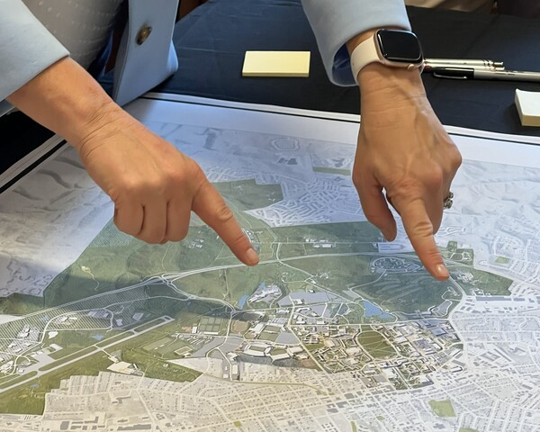 Two hands point at locations on a large printed map during a planning meeting.