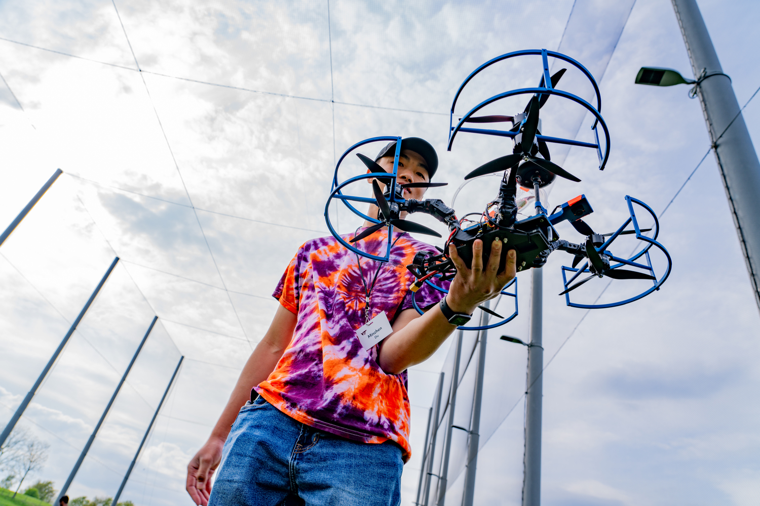 Man in hokie colors handling a drone outdoors.