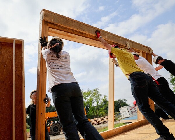 People helping build a frame for a house