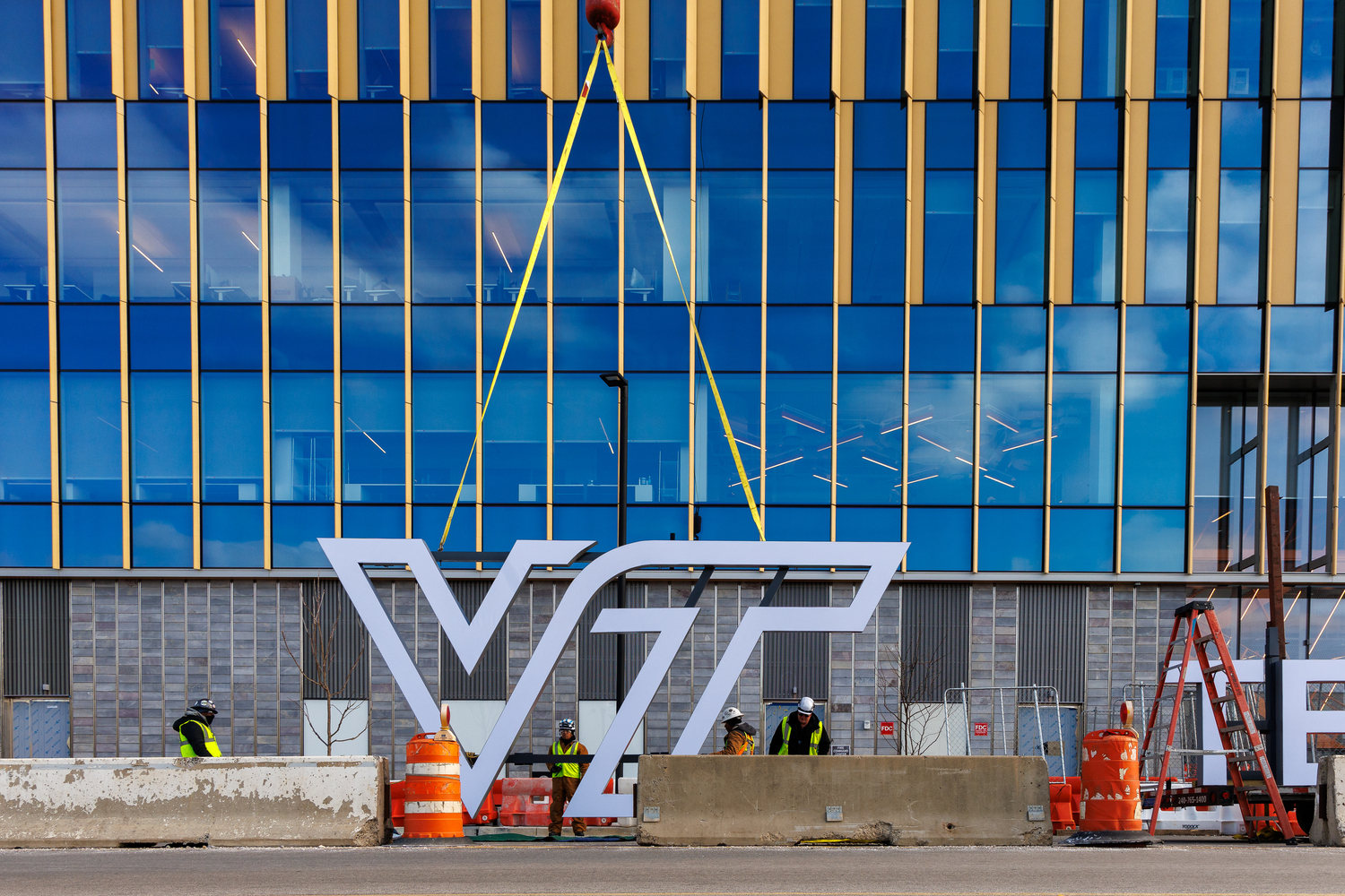 The Virginia Tech logo being installed on a building