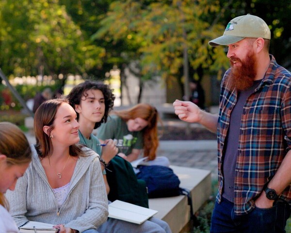 Professor educating a student while they sit outside