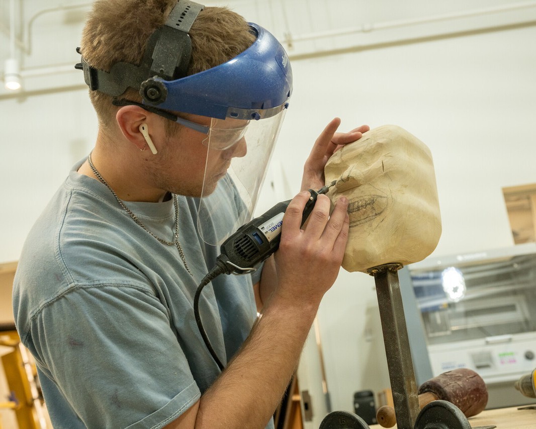 Man sketches face into wood