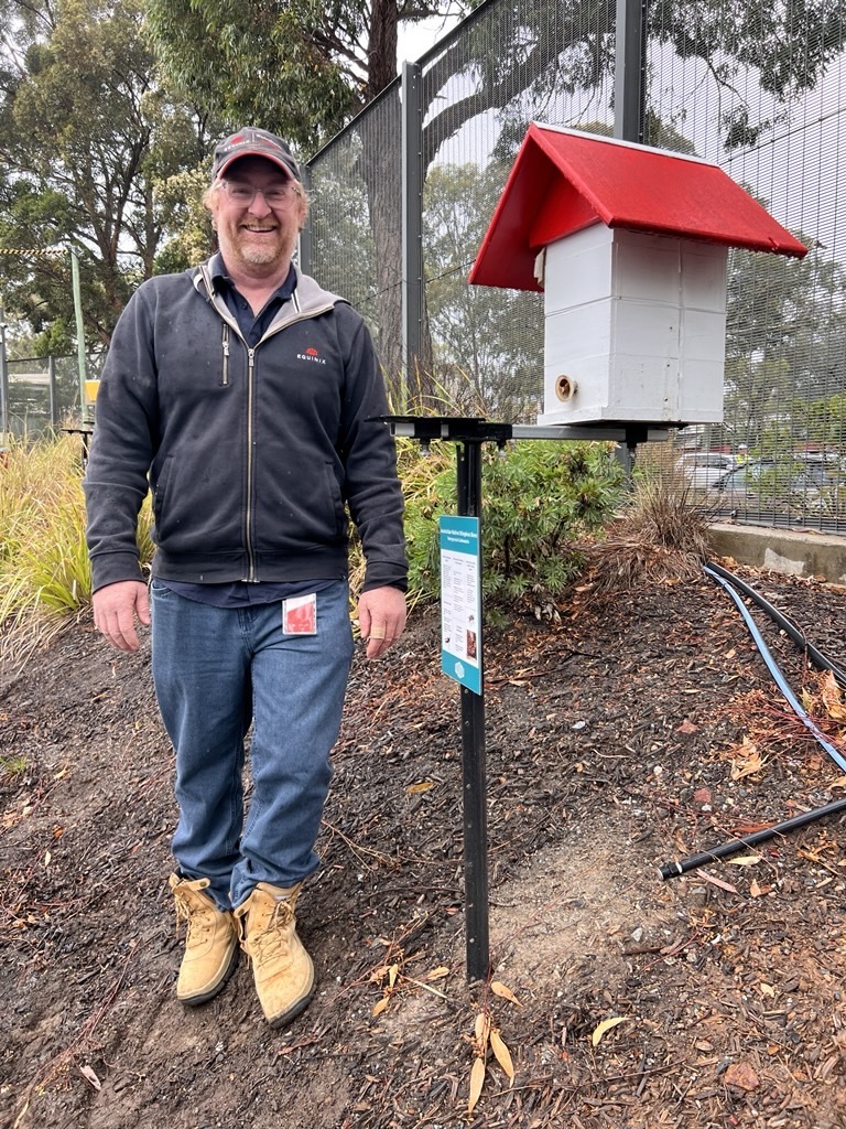 Matt stands next to a beehive. 