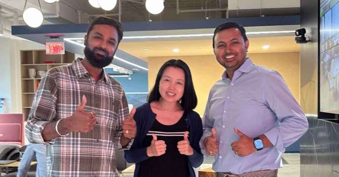 Three individuals giving a "thumbs up" in an office environment.