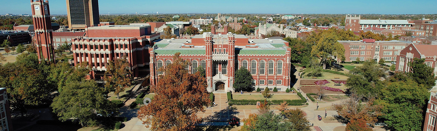 Aerial view of a university campus with several red‑brick buildings surrounded by trees and walkways.